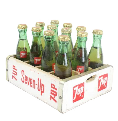 Vintage Seven-Up soda bottles in a wooden crate on a white background