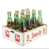 Vintage Seven-Up bottles in a wooden crate on a white background