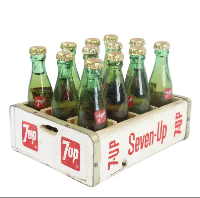 Vintage Seven-Up bottles in a wooden crate on a white background