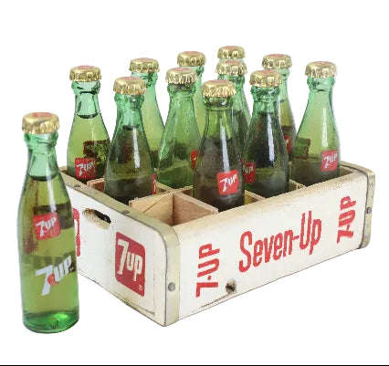 Vintage Seven-Up bottles in a wooden crate on a white background