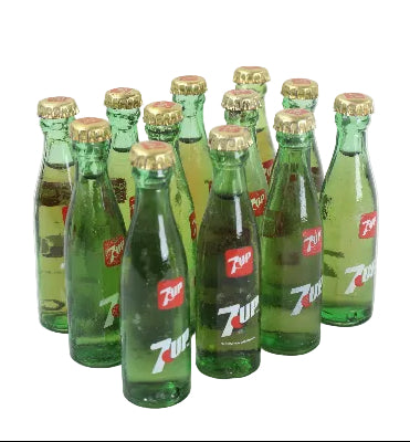 Collection of green glass bottles with gold caps on a white background