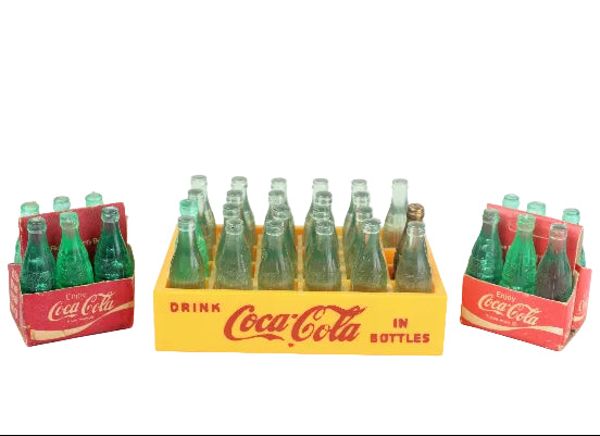 Set of miniature Coca-Cola bottles in vintage packaging on a white background