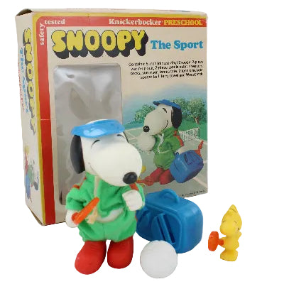Snoopy toy figure with sports equipment on a box labeled 'Snoopy The Sport' on a white background