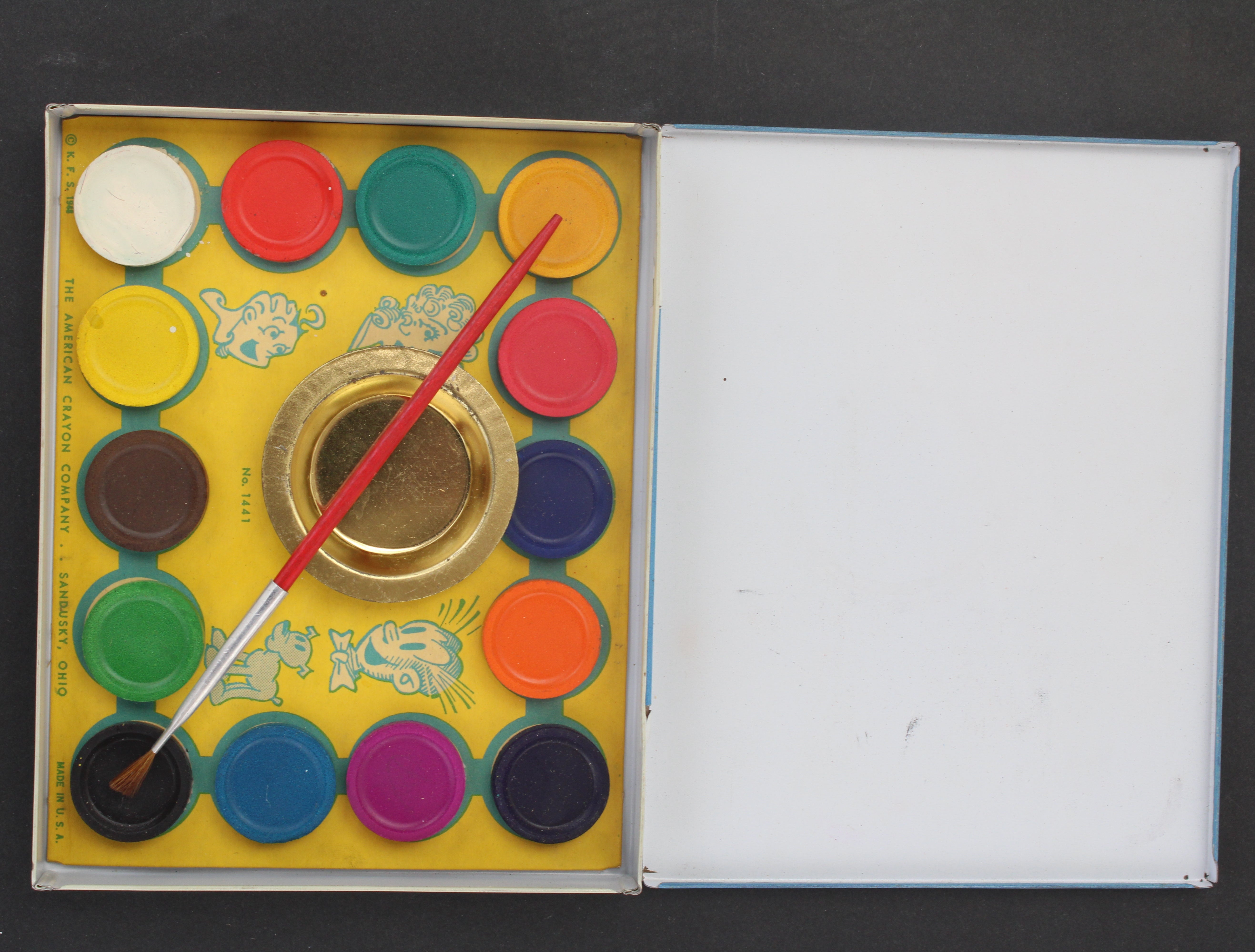 Set of Blondie watercolor paints with a brush in an open box on a dark background