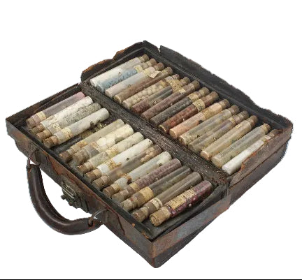 Set of vintage cylindrical objects in a wooden case on a white background