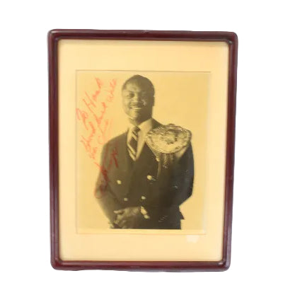Framed black and white photo of a Joe Frazier holding his heavyweight championship belt  on a yellowed background