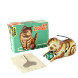 A vintage Chinese cat-shaped toy with a green and orange patterned body, shown next to its green illustrated box and a small metal key on a white background.