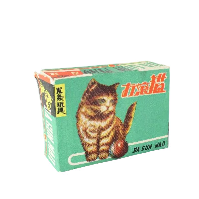 A vintage green cardboard box for Da Cun Mao cat toys, featuring an illustration of a fluffy brown tabby kitten playing with a red ball.