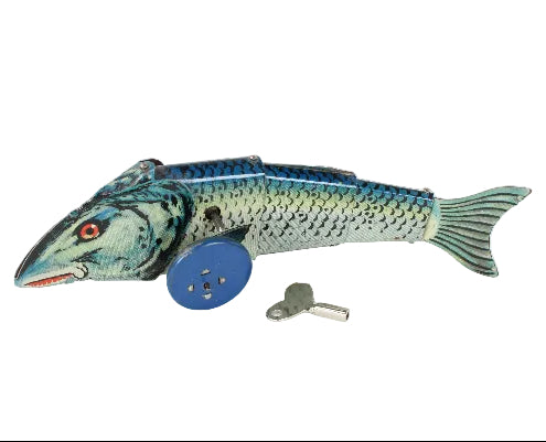 A vintage metal tin fish toy with blue wheels and a small metal key, photographed on a plain white background.