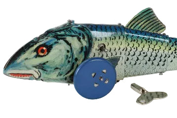 A vintage metal tin fish toy, likely a mackerel, featuring painted scales in blue, green, and silver, with a blue button for a wheel and a small metal key.