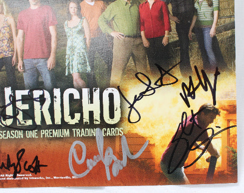 A close-up of a signed Jericho trading card featuring cast members from the television show, with multiple autograph signatures across the front. The card is photographed against a plain white background.
